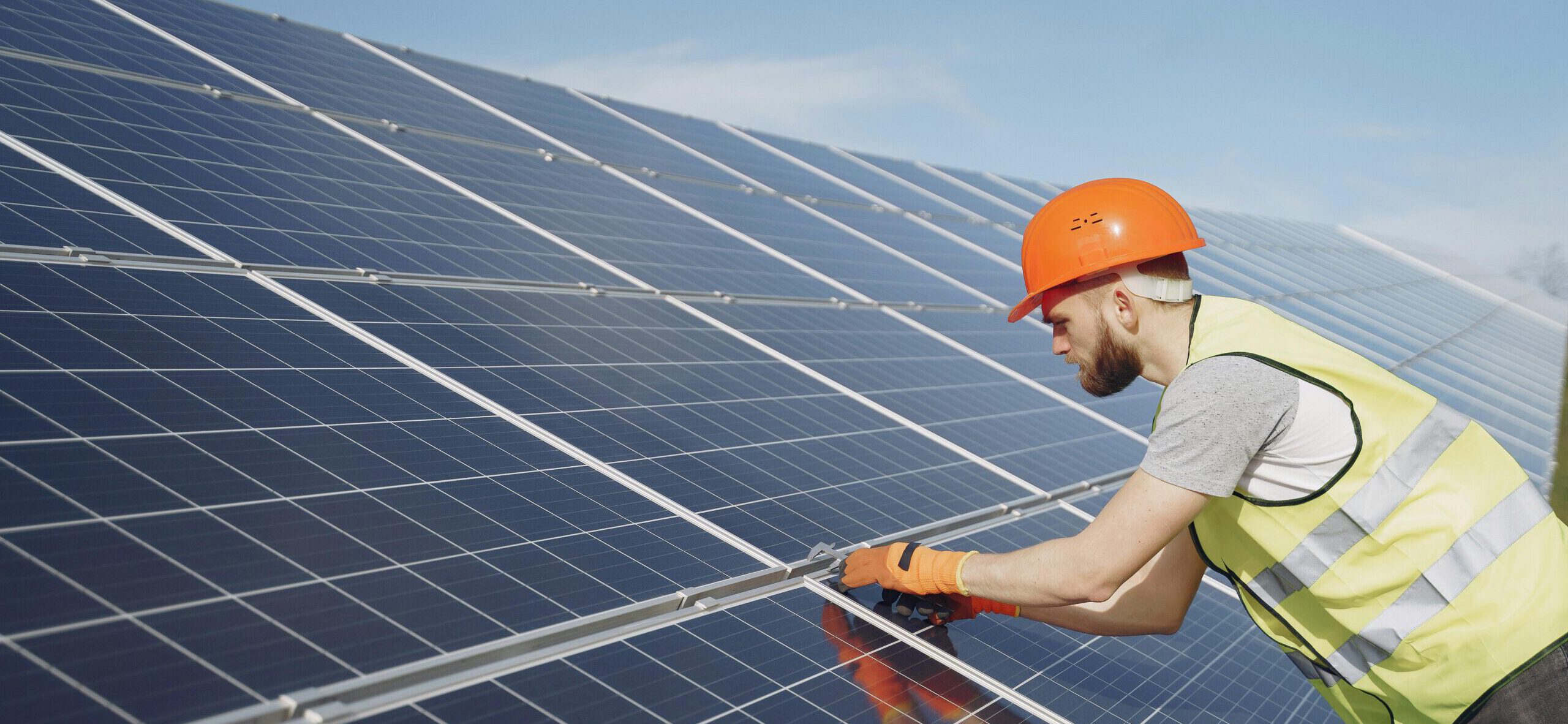 Technicien en équipement de protection individuelle installant des panneaux solaires photovoltaïques.