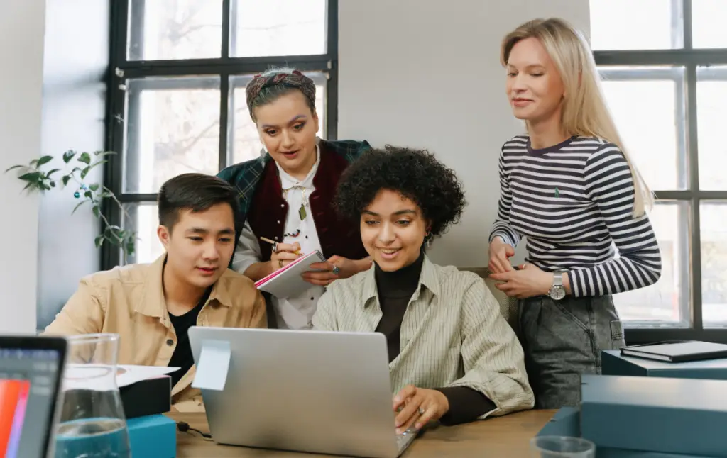 Équipe de stagiaires collaborant autour d'un ordinateur portable pour une formation sur-mesure.